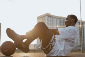 A young basketball player relaxing on an outdoor court during sunset.
